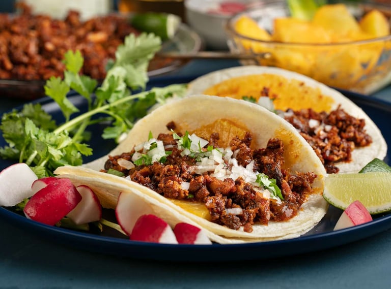 "Tacos Al Pastor served with fresh cilantro, onions, pineapple, and lime, ready to enjoy."