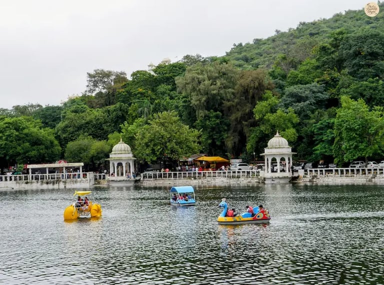 People enjoying boating and water sports at Dudh Talai Lake in Udaipur with surrounding hills in the backdrop.