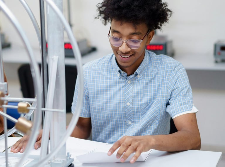 a researcher in a blue shirt is sitting at a table, writing a paper
