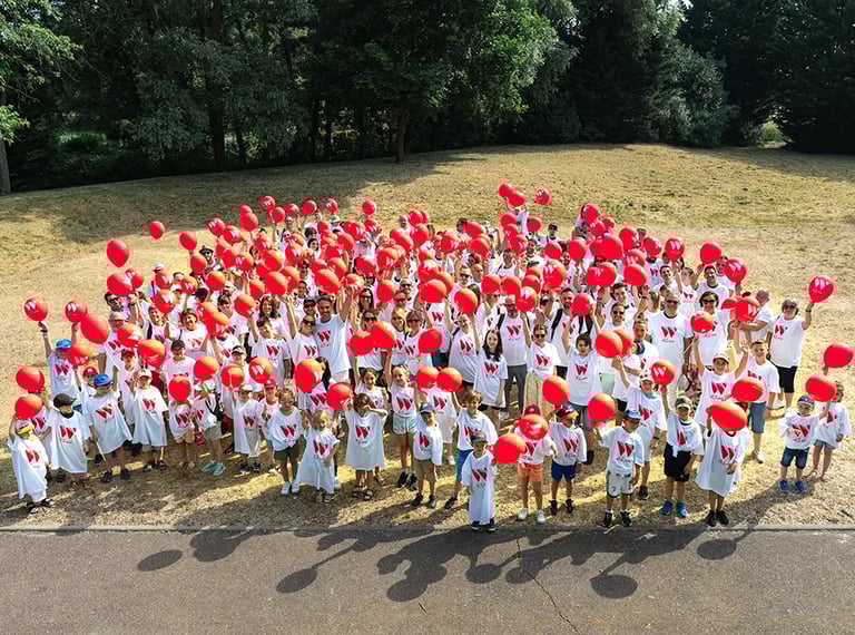 Photo de groupe festive avec ballons rouges pour la journée du personnel de l’entreprise Weigerding.