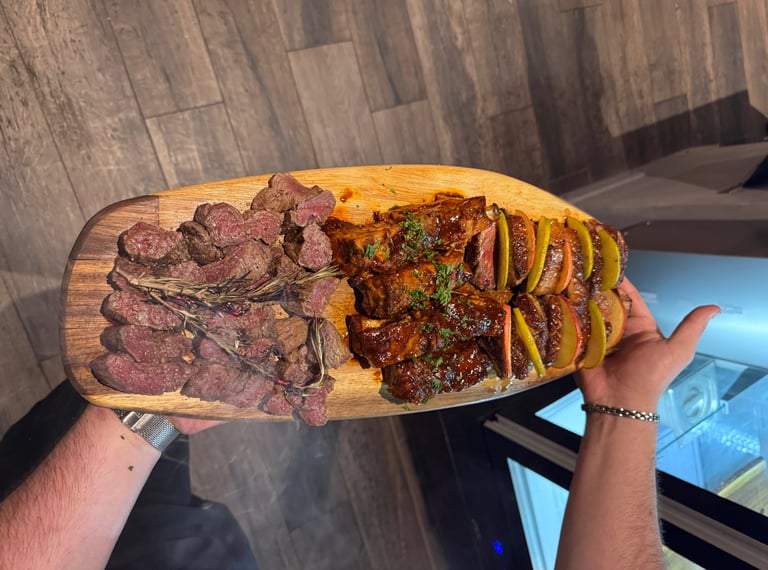 a person holding a large wooden board with steak steak and potatoes