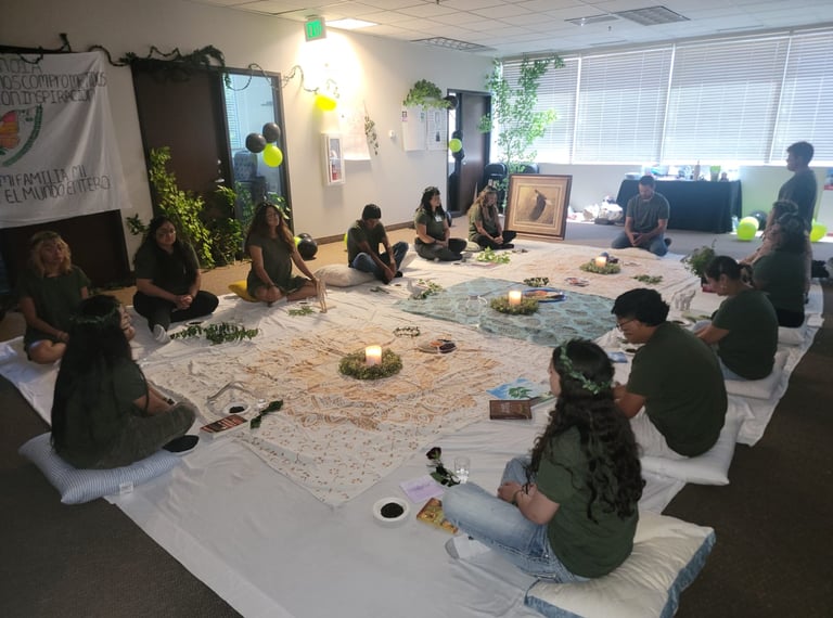 A group of people sitting in a circle on floor cushions for a spiritual healing ceremony with candles.