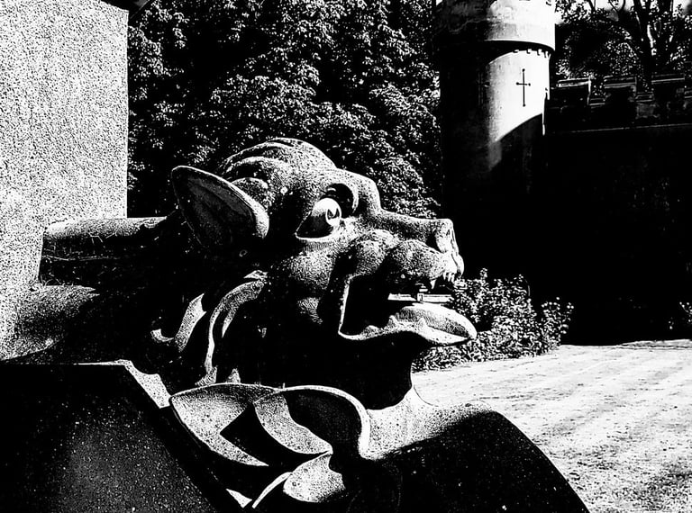 monochrome photo of a gargoyle with fortified tower in background