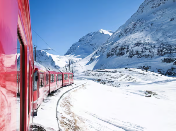 Bernina Express traveling through the snowy Alps on a sunny day.