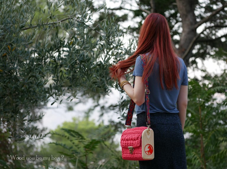 a woman with crocheted pink wooden crossbody bag with horse image