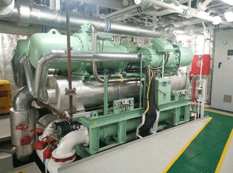 Industrial HVAC water-cooled screw chiller system in a ships plant room with insulated piping.