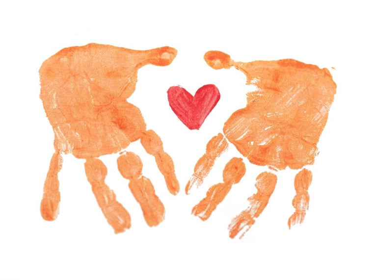 Dos huellas de manos naranjas rodeando un pequeño corazón pintado de rojo sobre un fondo blanco.