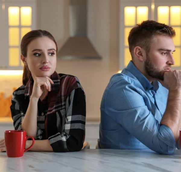 a man and woman sitting at a table avoiding talking