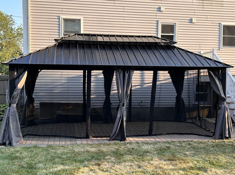 A 6-post gazebo assembled for a client in Peabody, MA. Black metal with gray privacy curtains and mosquito netting.