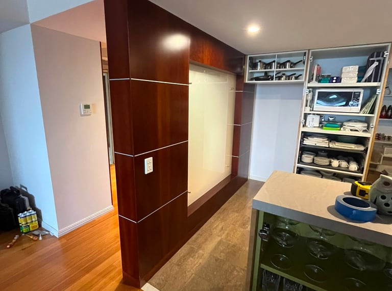 Modern home interior with mahogany wood paneling, hardwood floors, and organized kitchen storage shelving.