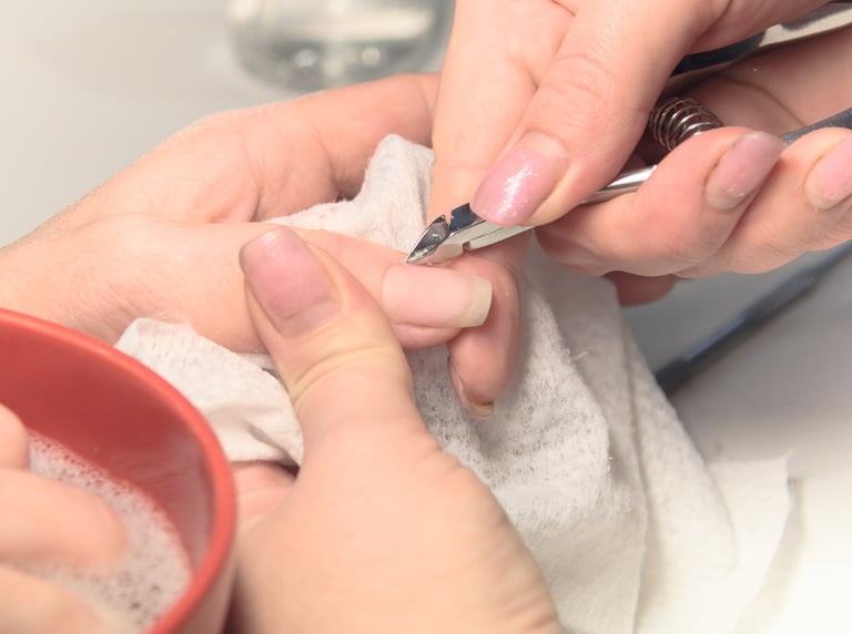Someone is performing a manicure and using a cuticle trimmer for precision