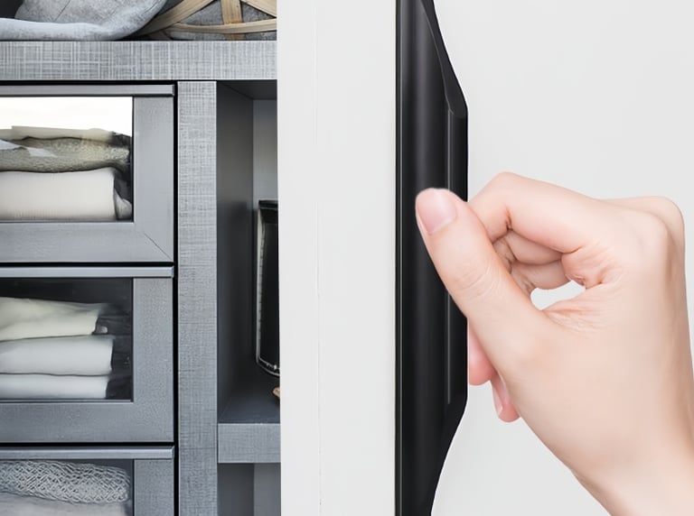 Black modern cabinet door pull handle: hand gripping the sleek black hardware on a wardrobe with fabric storage drawers