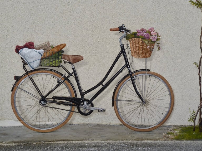 Un vélo peint en trompe-l'oeil sur une façade. Ses paniers emplient de fleurs et autres courses.