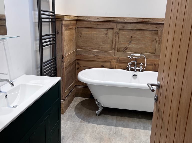 Finished bathroom with freestanding bath and wood-panelled walls.