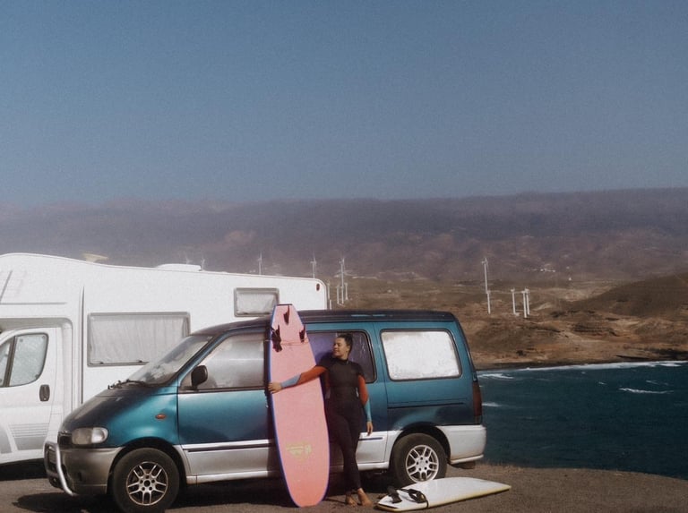 a man standing next to a van with a surfboard