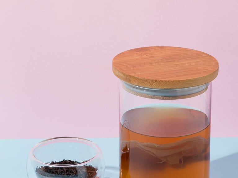 Té de kombucha casero fermentando en un frasco de vidrio con un SCOBY y té negro.