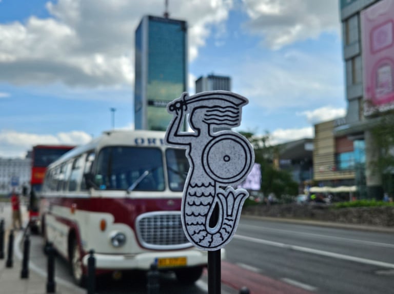 Magnes z Syrenką Warszawską na tle retro Busa w Warszawie