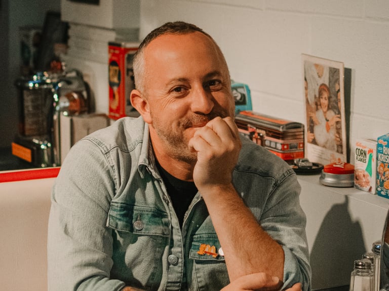 Photo of Dan Clapson sitting in a diner booth, taken in Calgary by Annie da Silva