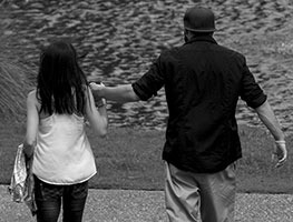 Black and white photo of a couple walking together outdoors near a body of water.