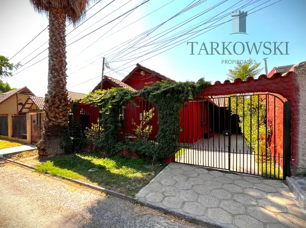 casa roja con cierre de reja y arbustos piso de cemente y área verde dentro y fuera a la venta