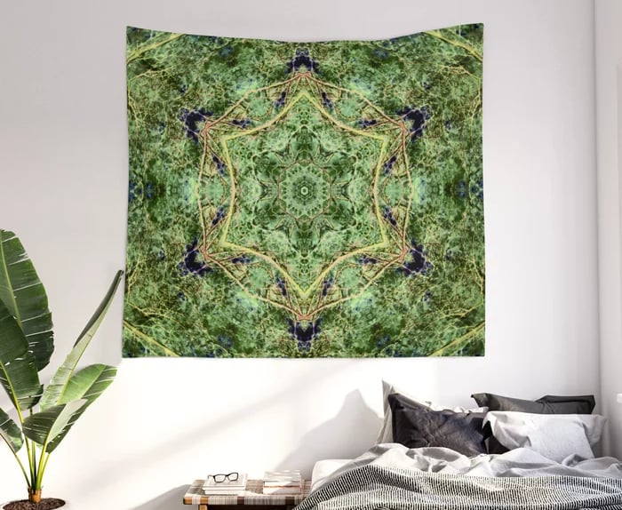 Tapestry on wall with bed underneath and a plant to the left of the bed