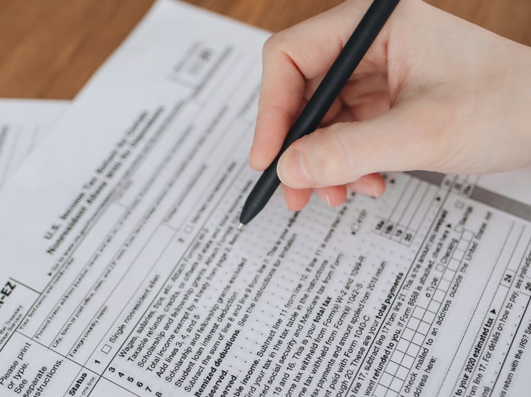 une main tenant un stylo, remplissant un formulaire.