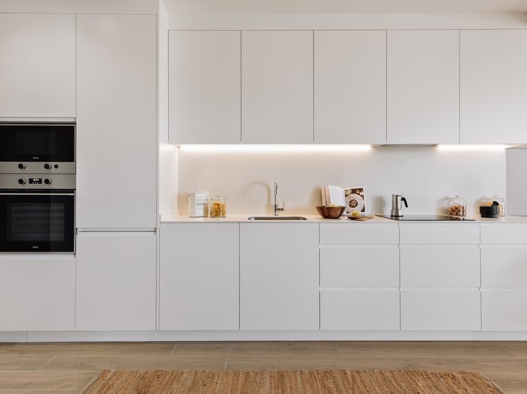 Open-plan kitchen with white cabinets and state-of -the-art appliances for contemporary apartment
