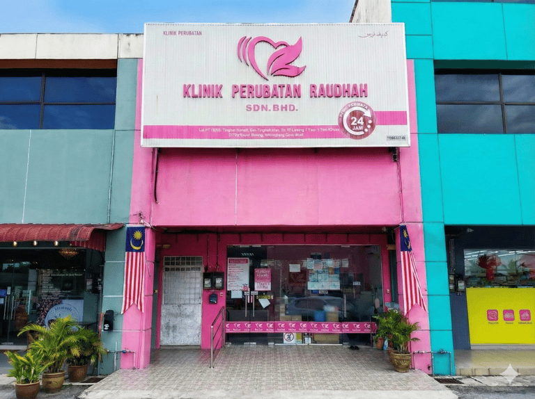 Pink storefront of Klinik Perubatan Raudah, a 24-hour medical clinic in Malaysia with glass doors.