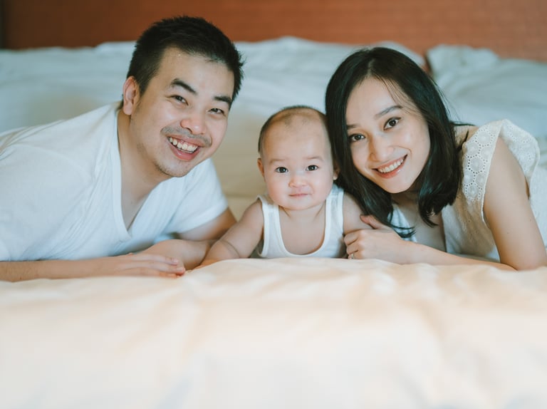 Parents and baby lying together on bed at Intercontinental Jimbaran captured in a natural indoor family photography session