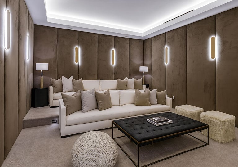 Luxurious home theater with custom wall panels, plush sofa, modern lighting, and stylish coffee table by Solo Home Decor.