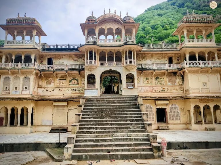 See the elegant Rajput-style temple architecture at Galta Ji Temple complex in Jaipur, surrounded by the Aravalli hills.