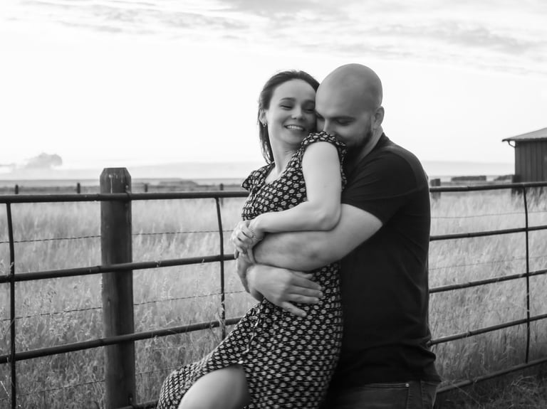 a man and woman are standing in front of a fence