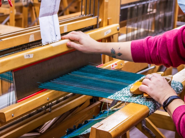 Student using a floor loom in one of our weaving classes.