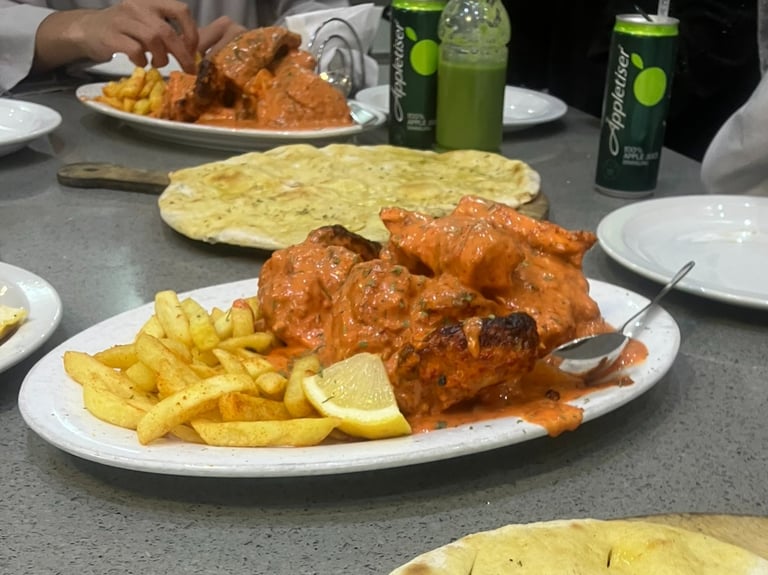 a table with peri-peri chicken, fries, naan, and drinks
