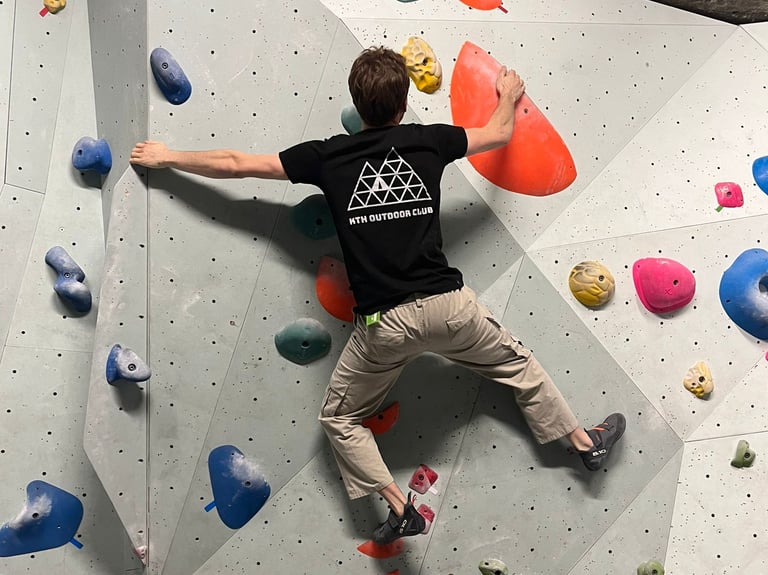 a man is bouldering on a wall in a climbing gym