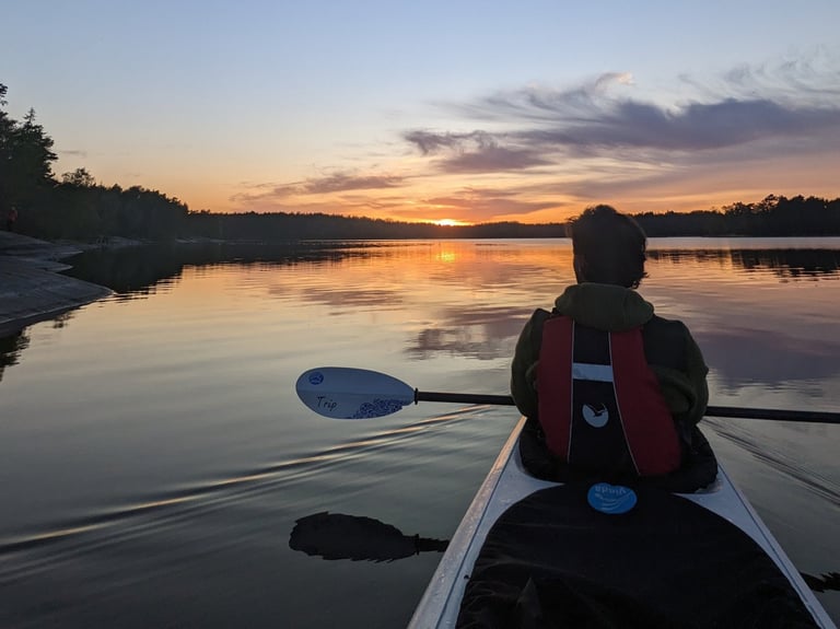 a person in a kayak paddling through the water (archipelago in Stockholm)