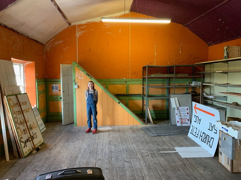 Renovation stage showing stripped hall with ladders, signs, and exposed surfaces.