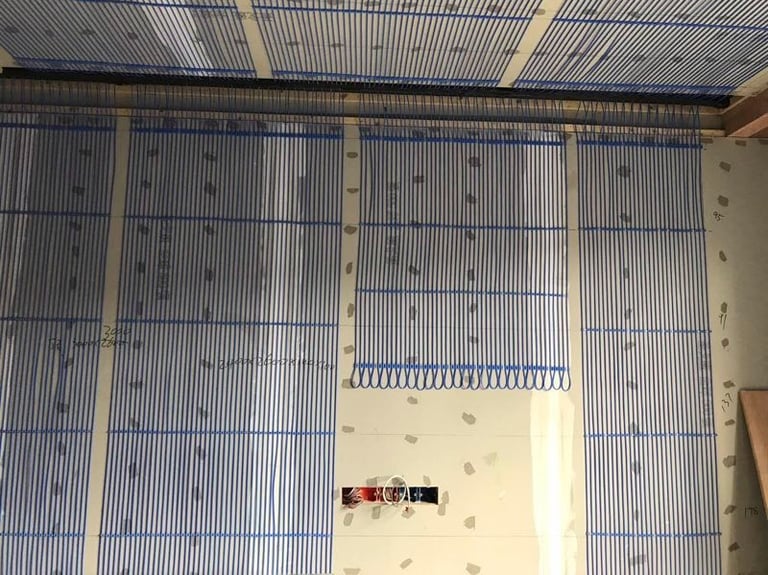 Blue capillary tube mats installed on a wall for an energy-efficient hydronic radiant heating and cooling system.