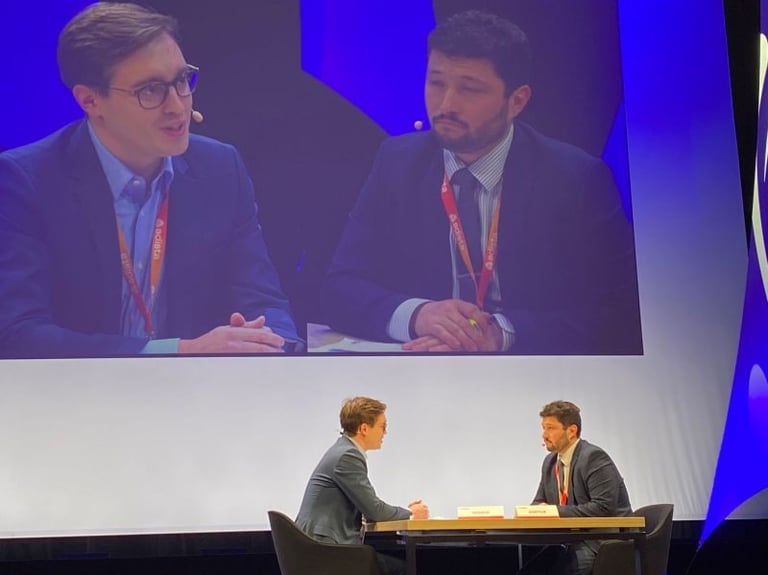 Two business professionals having a panel discussion on stage at a corporate conference event.