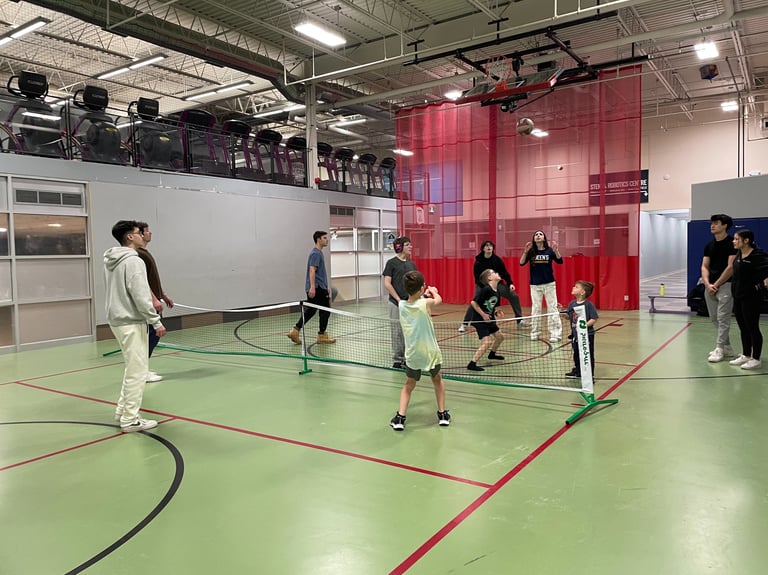 Children and QLeague Kids staff play an adaptive volleyball game in a gymnasium