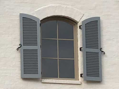 fixed louver shutters with decorative hardware to open and close and protect