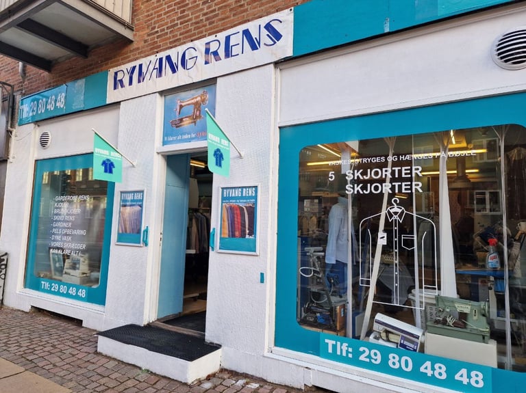 Facade af Ryang Rens butik med indgang og vinduer, der viser skilte og tekstilpleje-services.