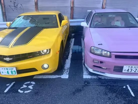 Fast and Furious replica cars: Yellow Camaro and Pink Skyline in Tokyo.