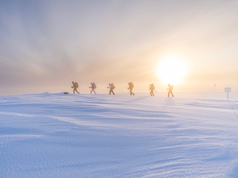 a group of people walking across a snow covered ground