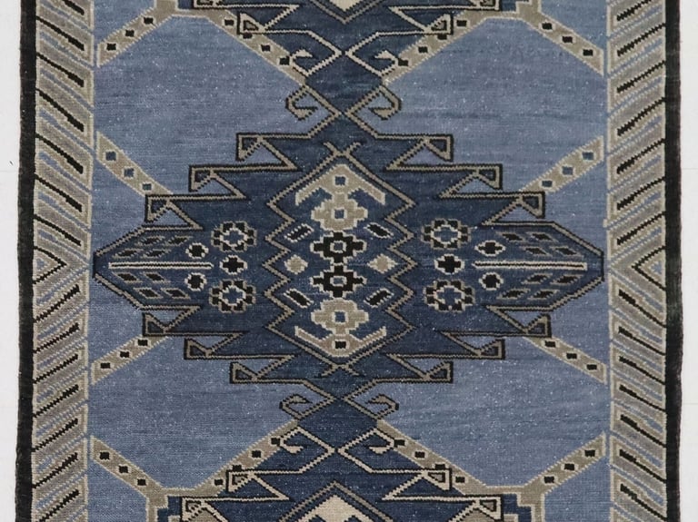 A light blue and navy geometric patterned area rug featuring traditional tribal designs.