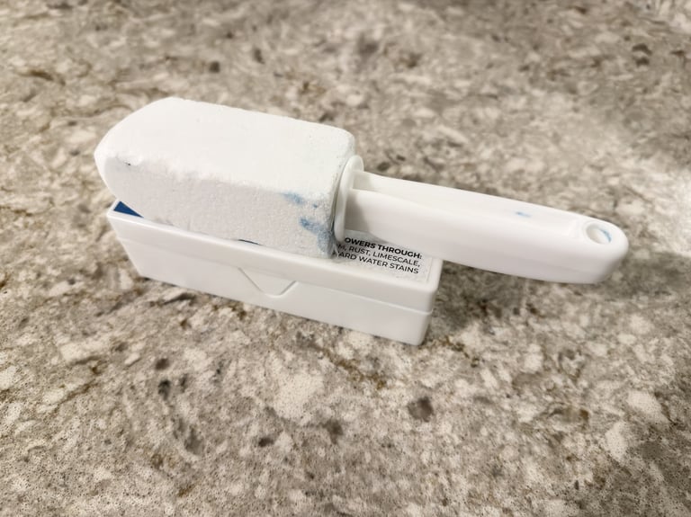 Pumice stone toilet cleaner resting on its container on a bathroom counter ready to scrub hard water