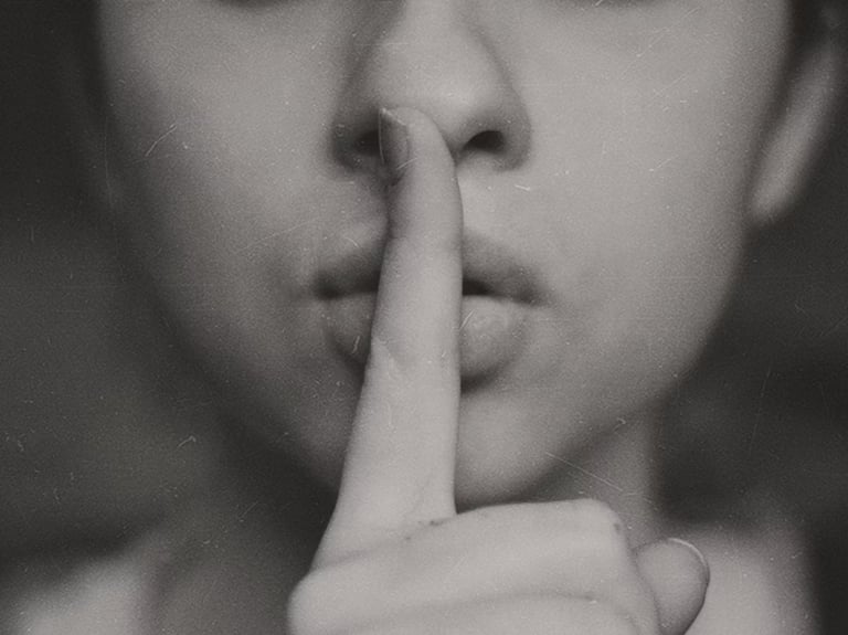 El dedo indice de una mujer sobre sus labios cerrados en señal de "ssshhh".