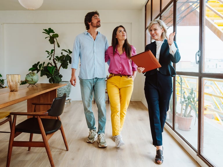 a man and woman walking through a room with a laptop