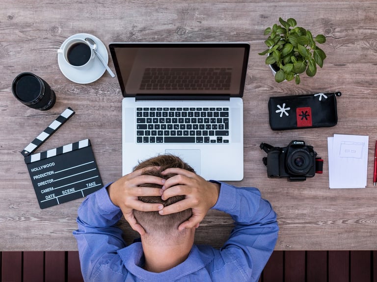 a man sitting at a desk with a laptop and a camera