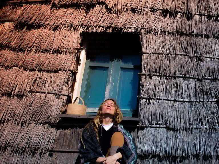 woman sitting in front of ancient sardinian house